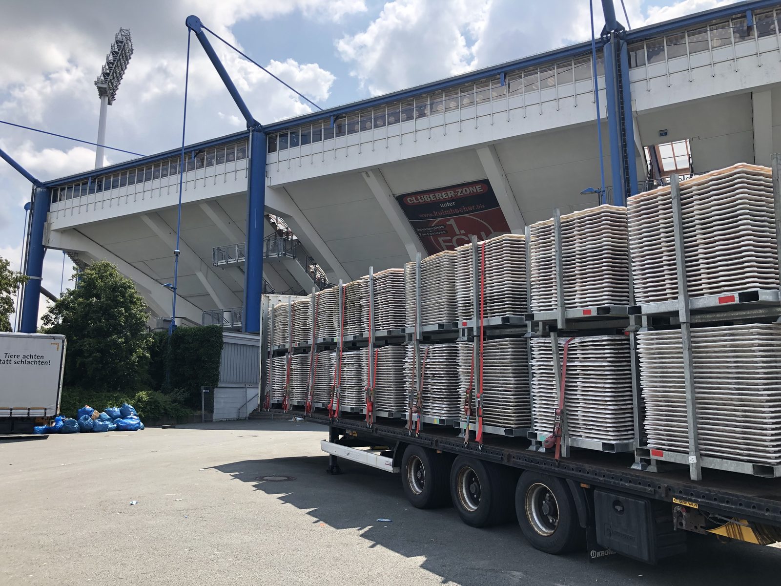 Sattelauflieger mit gestapelten Bodenschutzplatten, mit Spanngurten für den Rücktransport gesichert.
