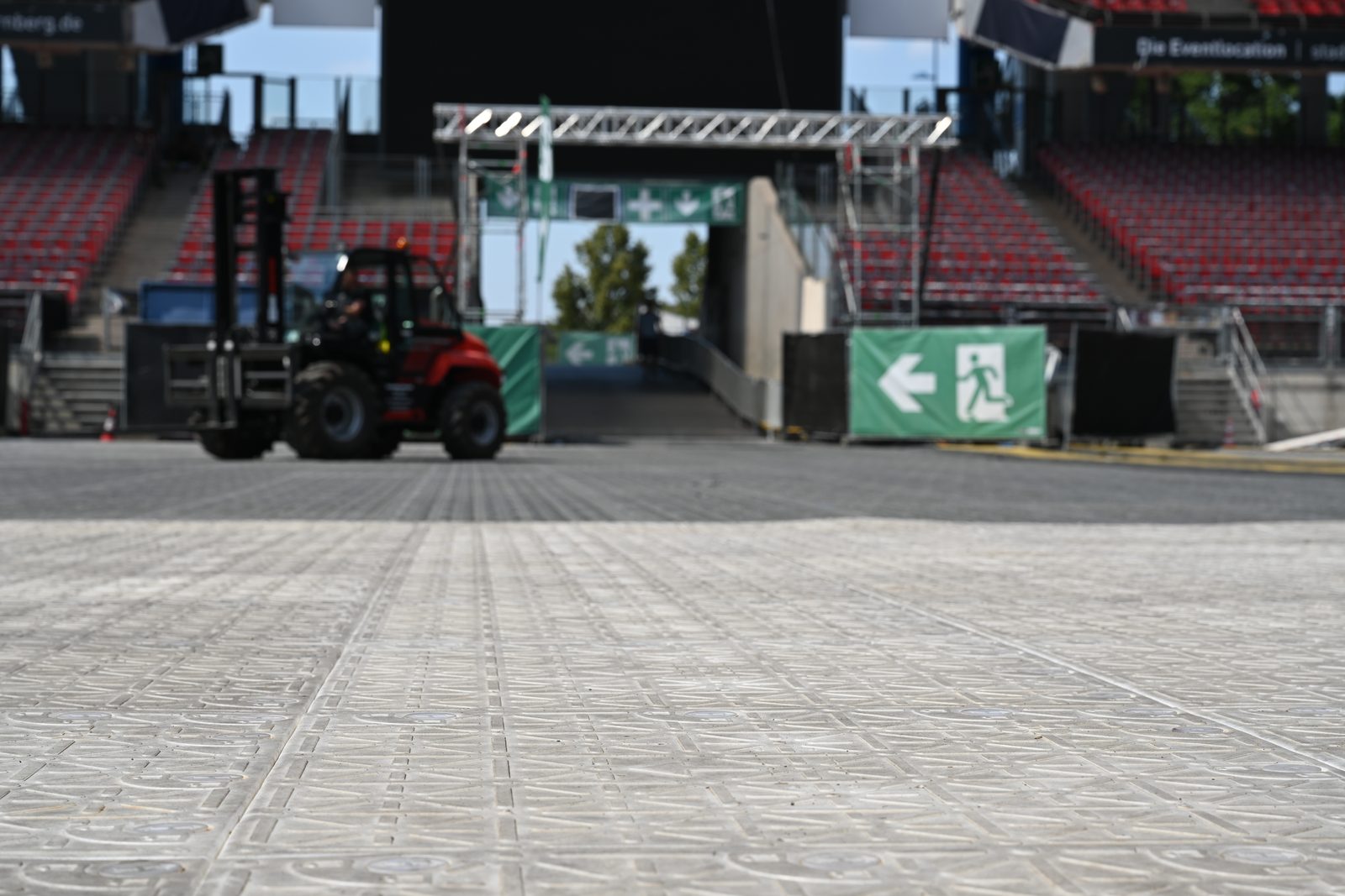 Bodenschutzplatten als Fahrweg im Stadion, dahinter ein Stapler und grüne Fluchtwegkennzeichnung