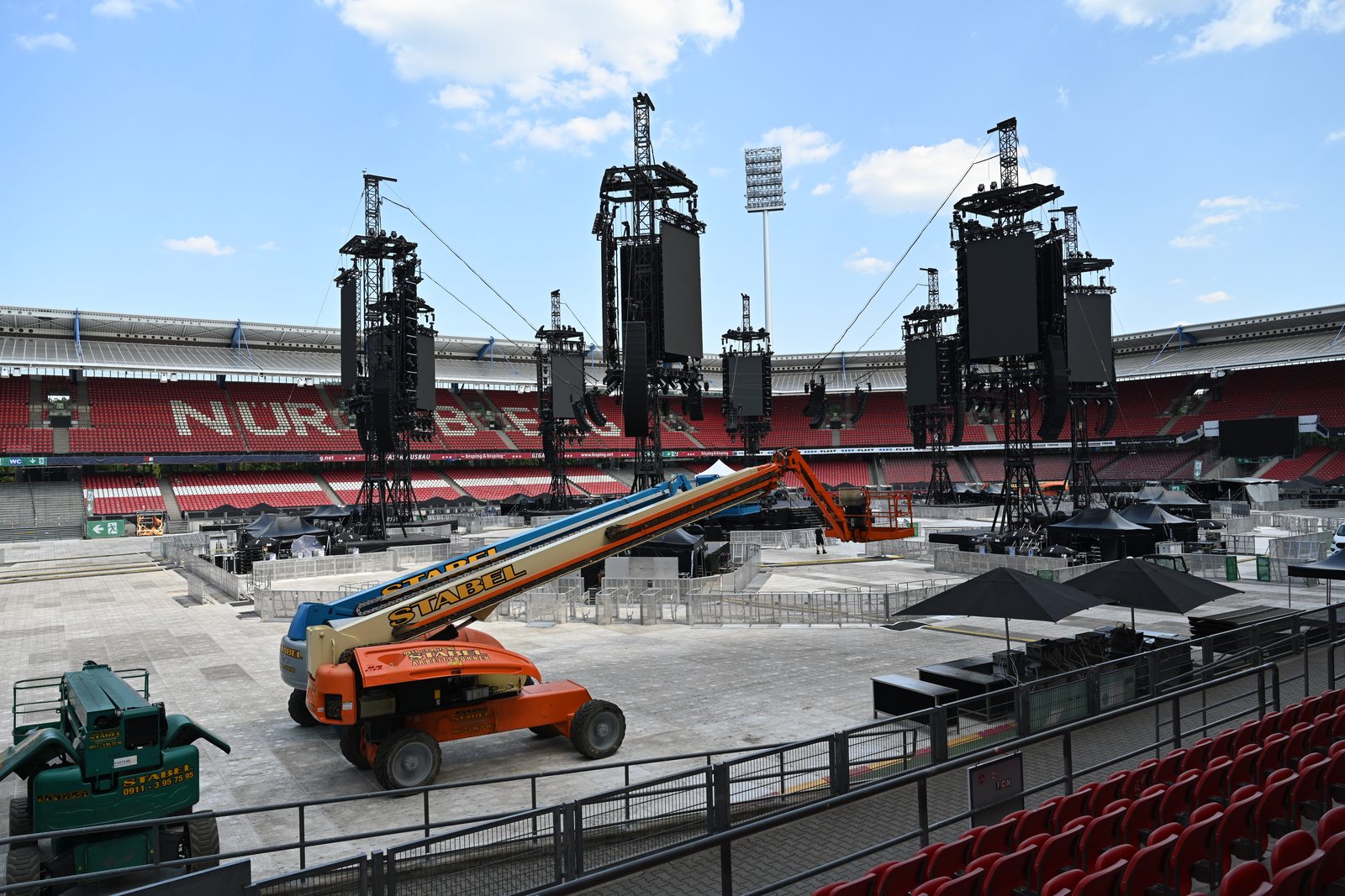 Bühnenkonstruktion aus Traversentürmen im Stadion, davor eine Arbeitsbühne auf abgedeckter Fläche