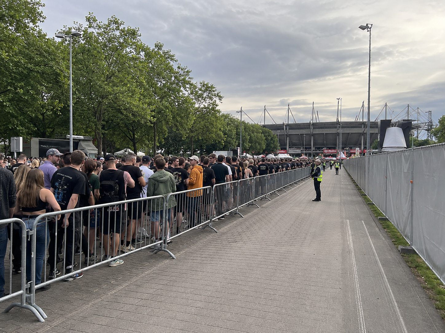 Wegführung am Stadionzuweg: Warteschlange hinter Absperrgittern neben einer freigehaltenen Spur für den Dienstverkehr