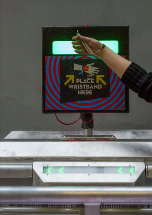 Akkreditierung bei Veranstaltungen: Hand hält ein Armband an das RFID-Lesegerät einer Drehsperre
