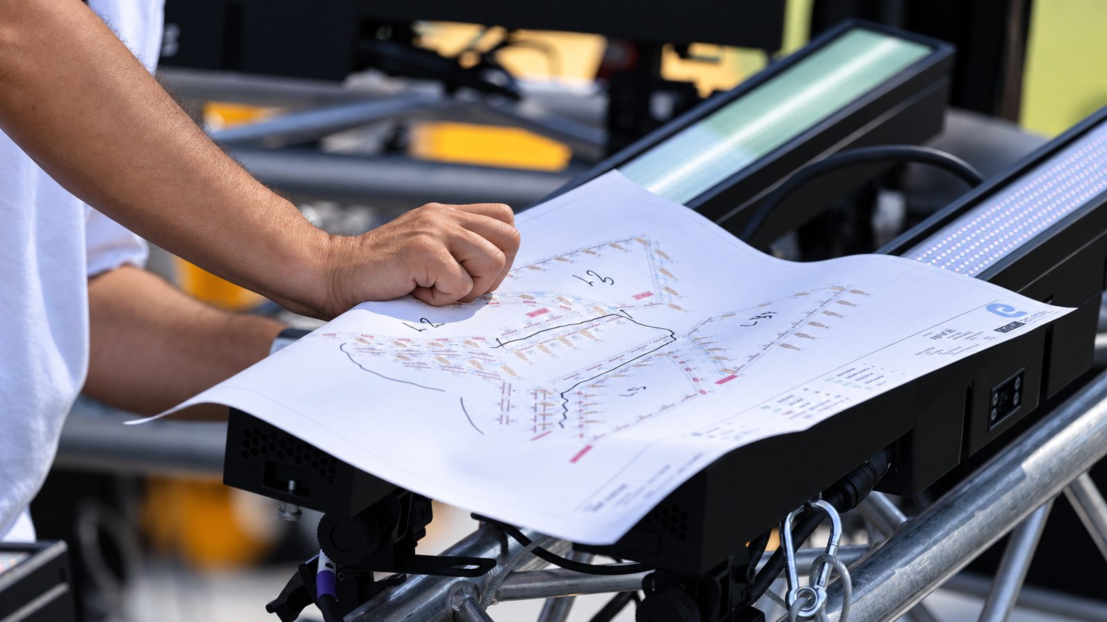 CAD-Plan als Ausdruck mit handschriftlichen Eintragungen, von einer Hand beschwert, auf einer Traverse im Freien.
