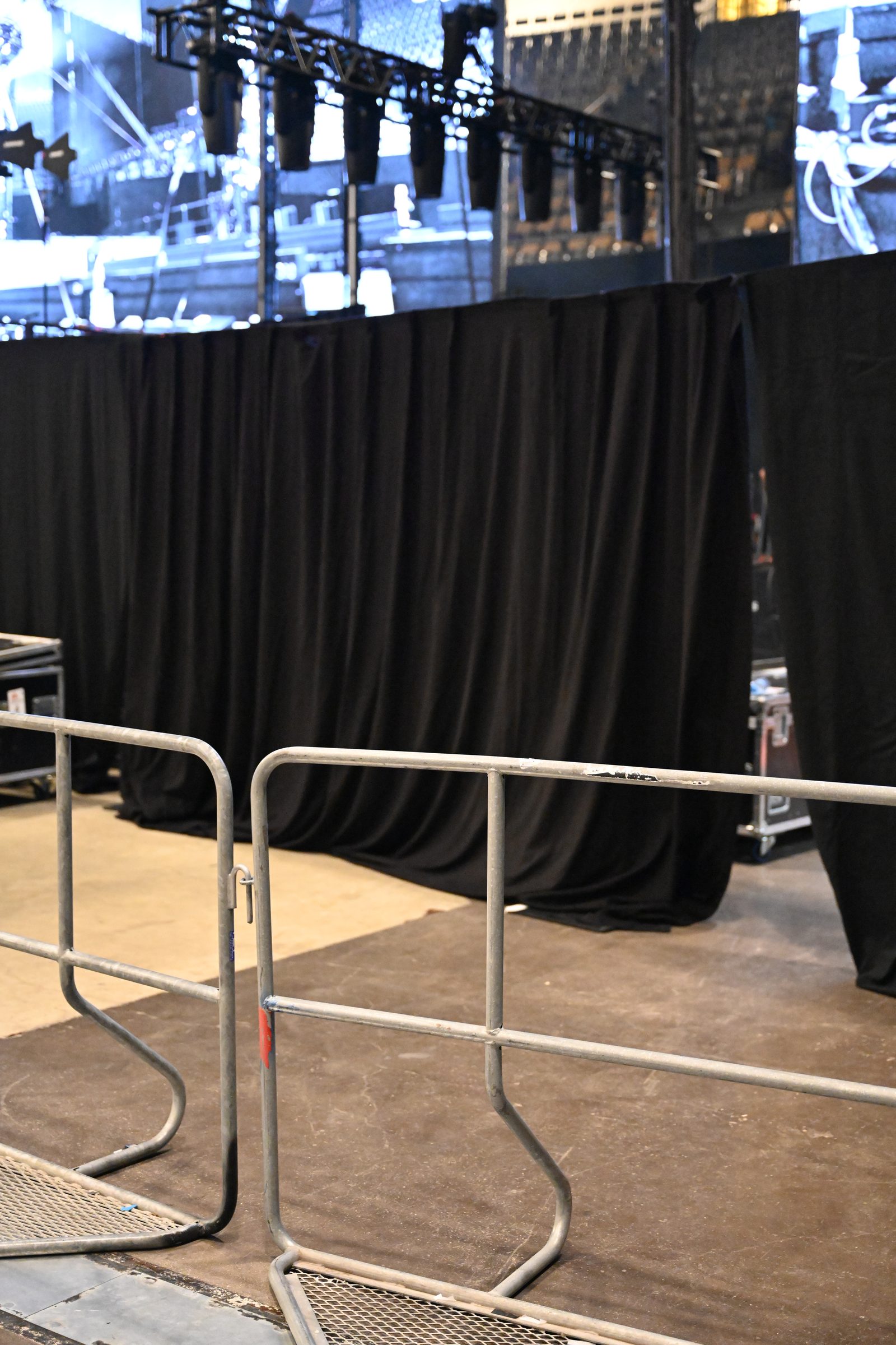 Zwei verzinkte Absperrgitter trennen den Backstage-Bereich vor einer schwarzen Molton-Wand ab, davor Bodenschutzplatten