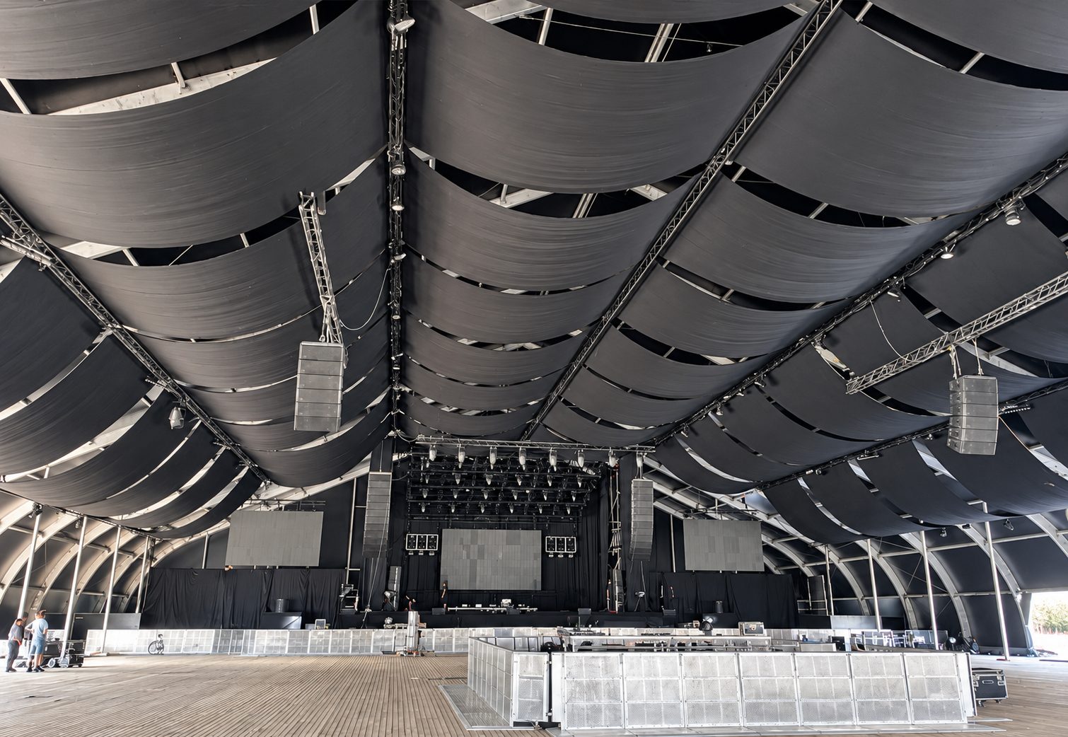 Aufbau in einer temporären Membranhalle: Traversen mit Line-Array-Lautsprechern unter geschwungenem Dach
