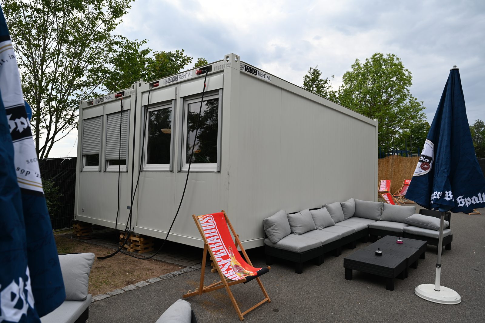 Green Room als weißer Raumcontainer mit grauer Lounge-Sitzgruppe und Couchtisch im Backstagebereich