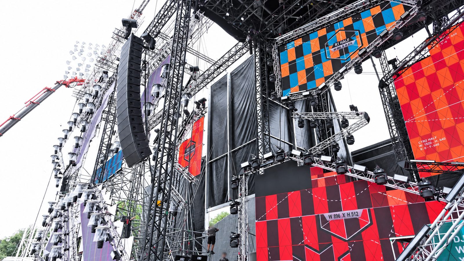 Open-Air-Bühne im Aufbau mit LED-Wänden im Testbild und hängendem Line-Array an Traversentürmen