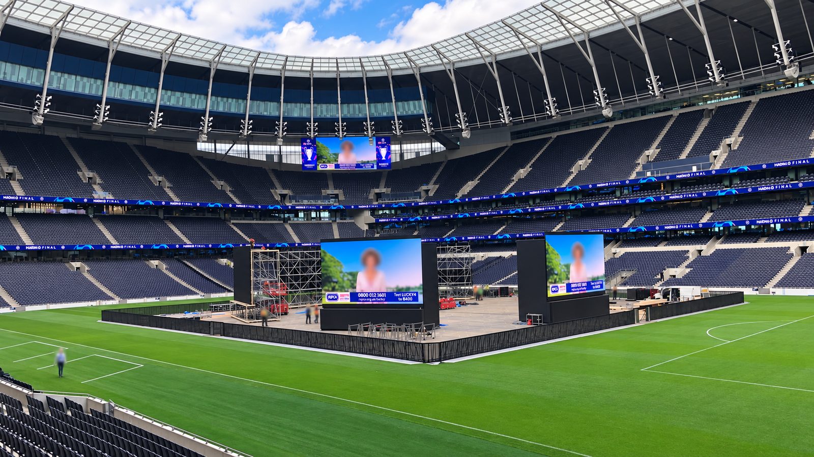 Bühnenaufbau mit zwei LED-Wänden im Stadioninnenraum, ringsum freier Rasen mit Spielfeldlinien