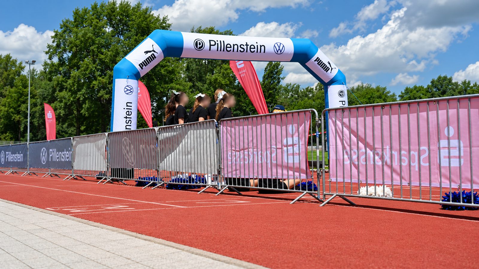 Zielbereich mit aufblasbarem Bogen, davor eine Reihe teils bannerverkleideter Absperrgitter auf der Tartanbahn