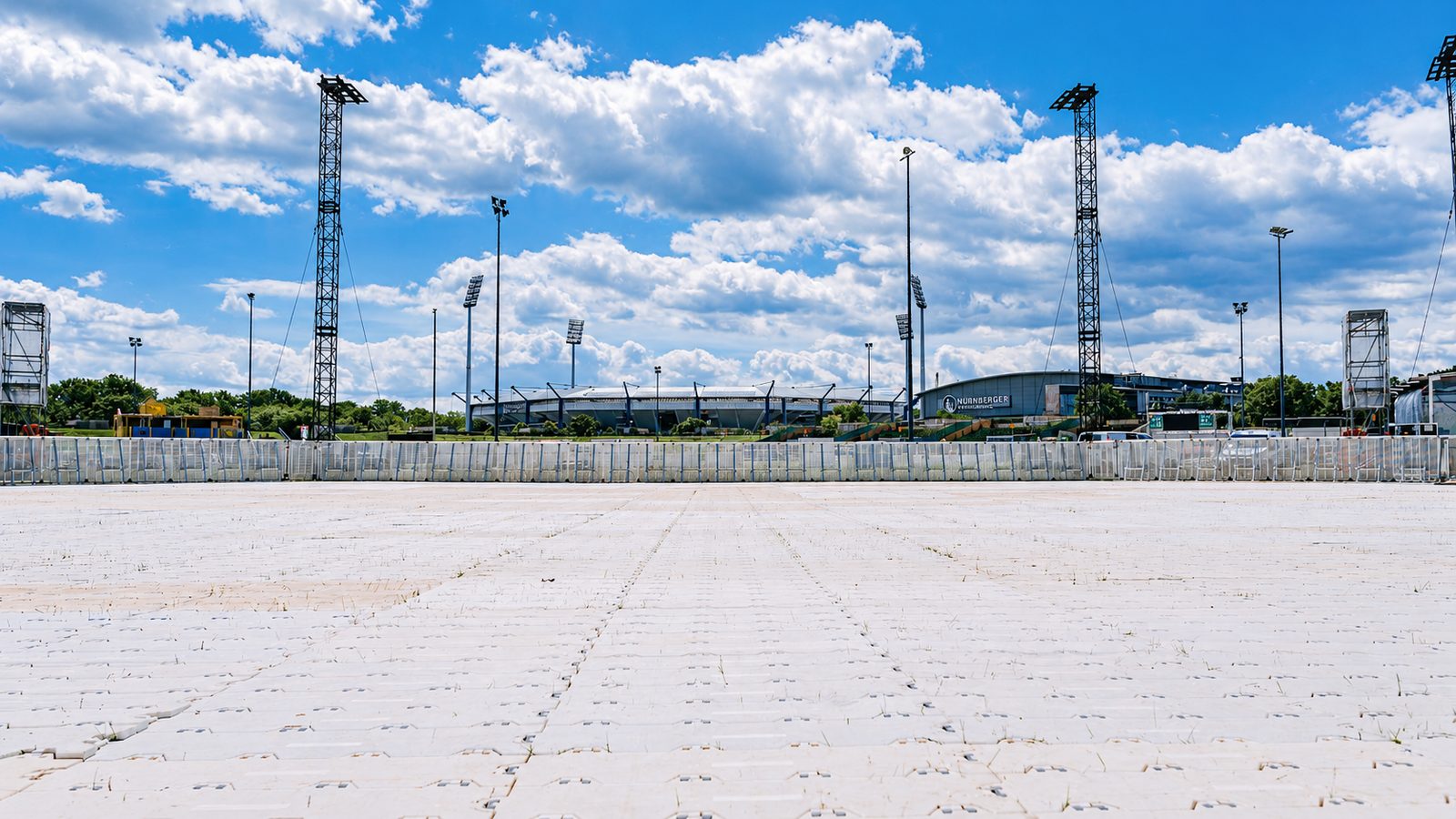 Supa Trac Fläche vor einem Stadion, weiße Plattenstraße mit Absperrgittern am Rand