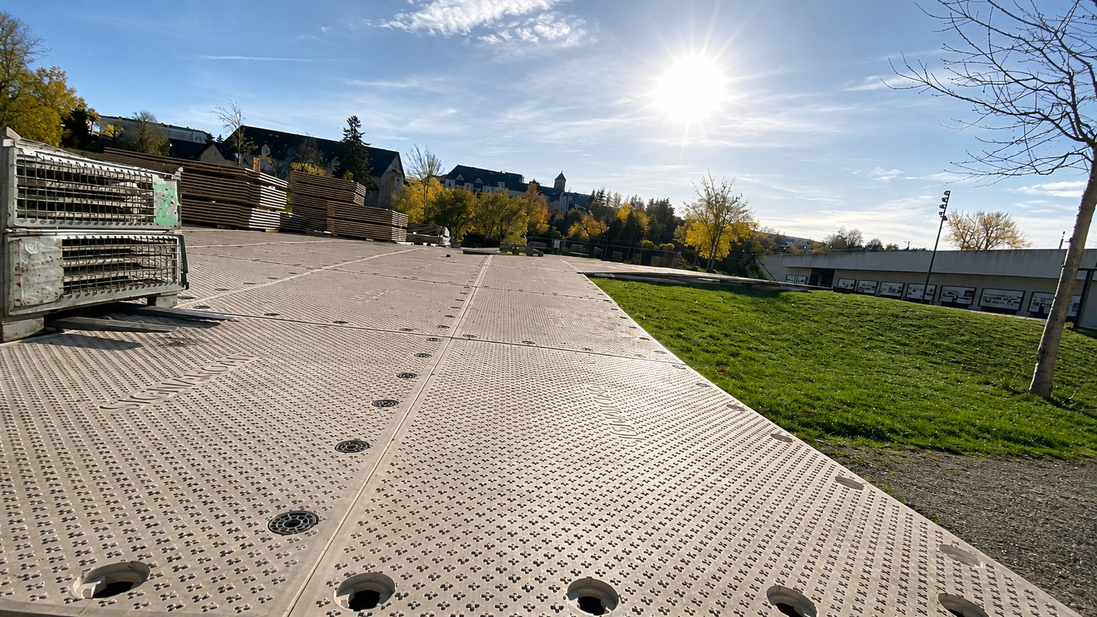 Trackway-Platten mit Lochung und Antirutschprofil führen über eine Wiese, rechts die Kante zum offenen Rasen