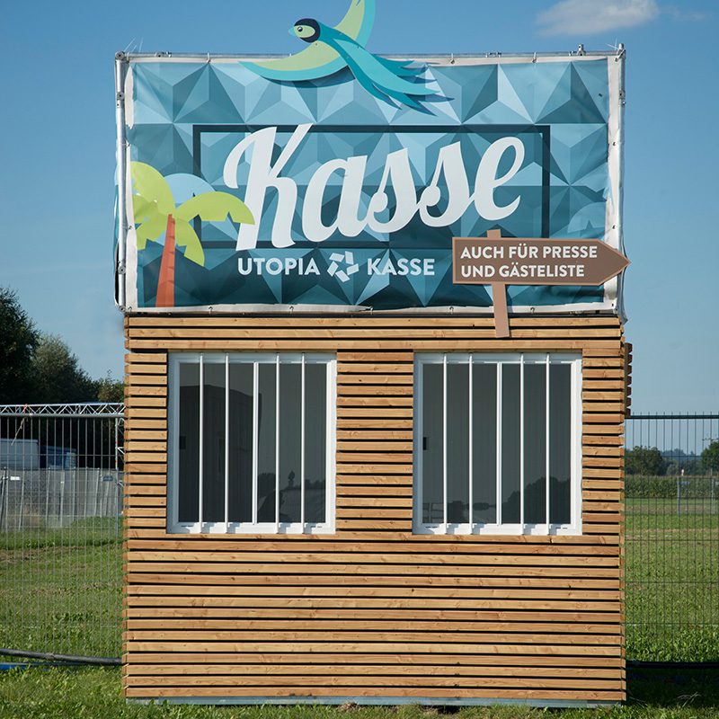 Ticketing bei Veranstaltungen: hölzerne Kassenhütte mit großem Banner Kasse und Wegweiser zur Gästeliste