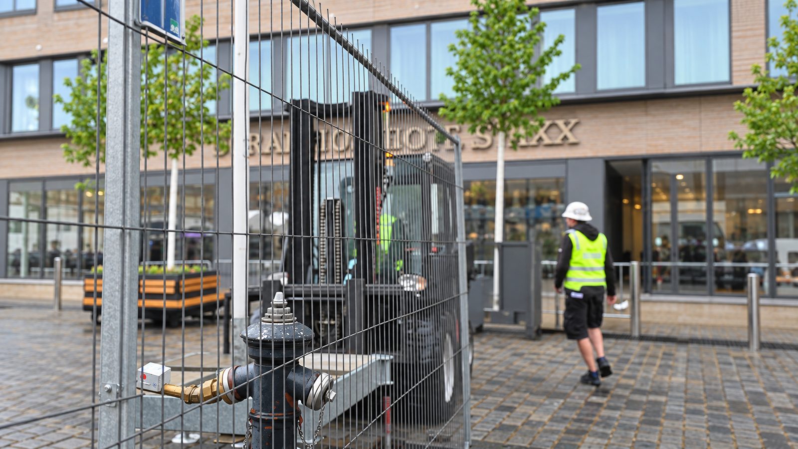 Umzäunung aus engmaschigen Mobilzaunfeldern sichert einen Aufbauplatz vor einer Hotelfassade ab
