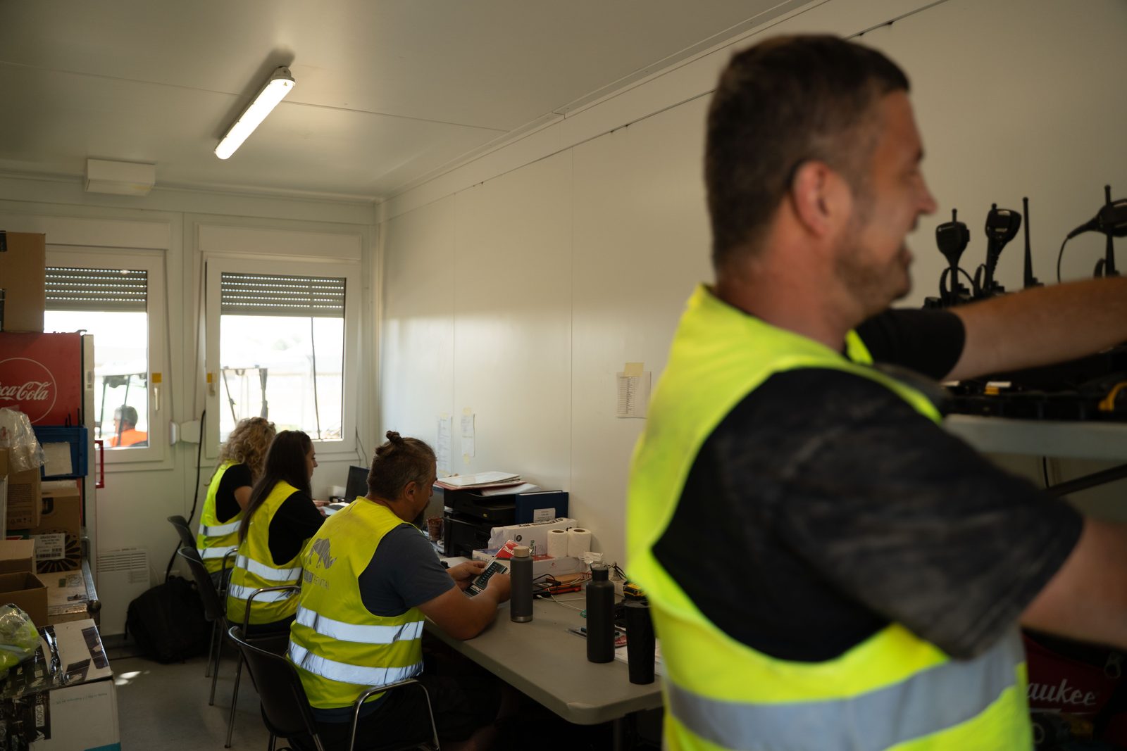 Veranstalter: Koordinationsteam in Warnwesten im Produktionsbüro, Handfunkgeräte in der Wandladestation