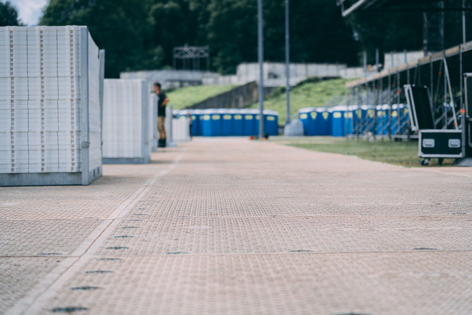 Rundgang über eine verlegte Fahrstraße aus Bodenschutzplatten, rechts Tribünengerüst, hinten Mobiltoiletten