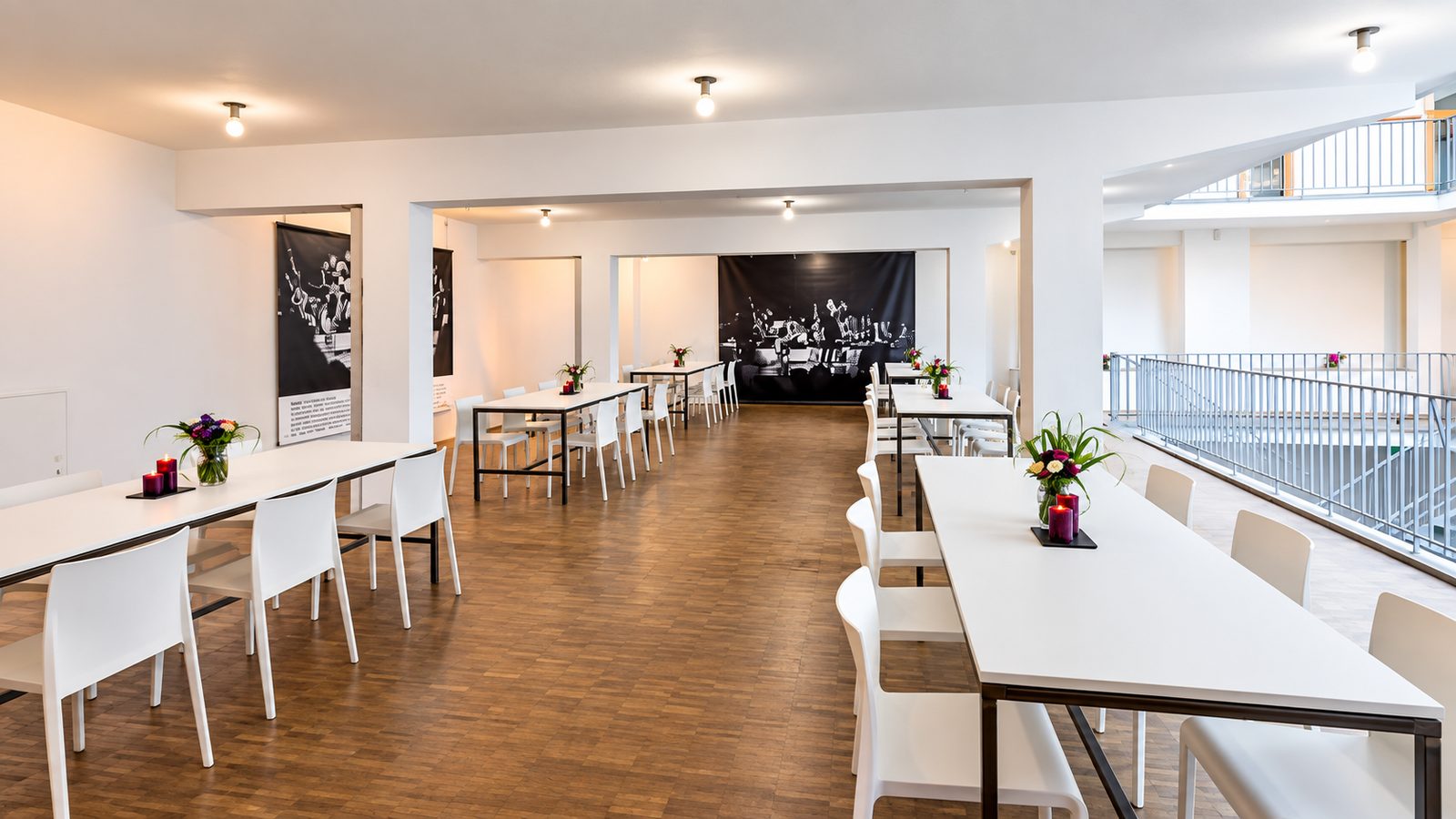 Zonenkonzept Veranstaltungen: freier Holzboden-Gang zwischen bestuhlten Tafeln, rechts ein Galeriegeländer.